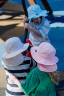 Three children wearing luma sun hats playing in a playground.